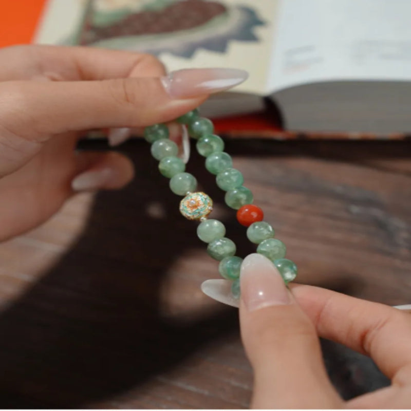 WhisperCrystal™ Natural Green Aventurine and Red Agate Bracelet featuring polished 8mm green aventurine beads, a vibrant red agate accent, and an elegant enamel-inspired charm in a Dunhuang-inspired color palette.